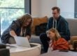 Three coworkers gather around a laptop in conversation