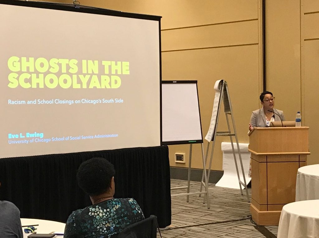 Eve L. Ewing presents from the podium at a gathering of StriveTogether communities. The slide shares the title of her book "Ghosts in the Schoolyard: Racism and School Closings on Chicago's South Side."