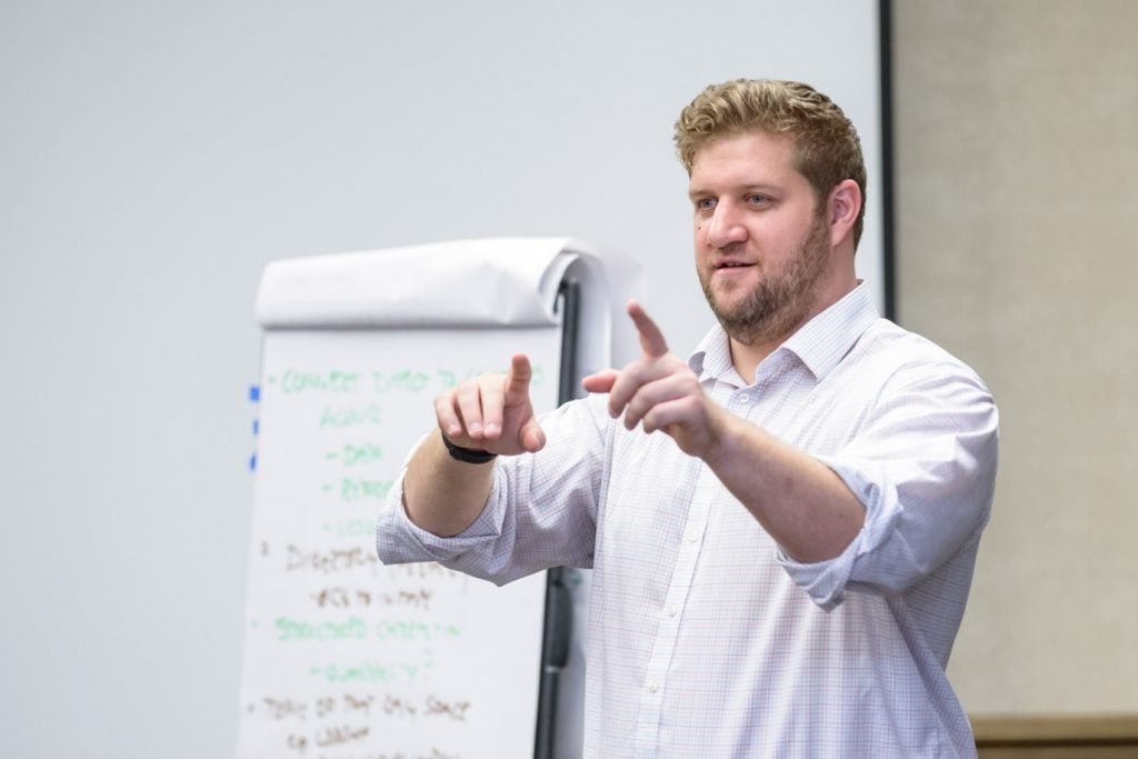 Colin Groth standing in front of a board speaking