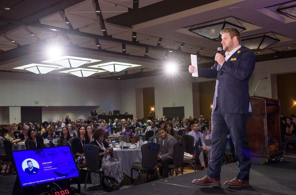 Colin Groth standing on a stage speaking to an audience