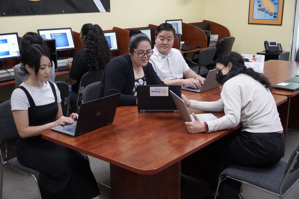 High school students sitting around a table with laptops