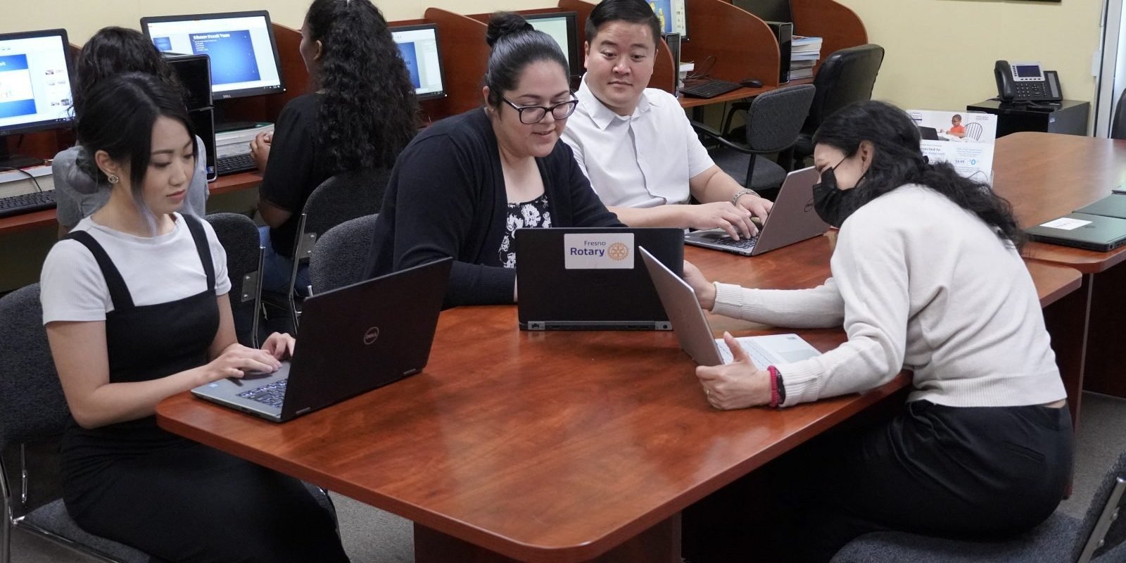 High school students sitting around a table with laptops