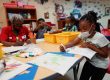 Children and an adult sit around a table coloring
