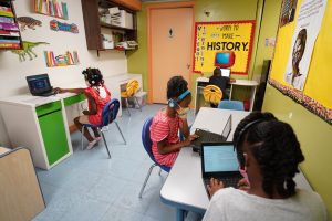 Three young students work on laptops at desks