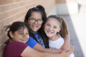 Three young students hugging