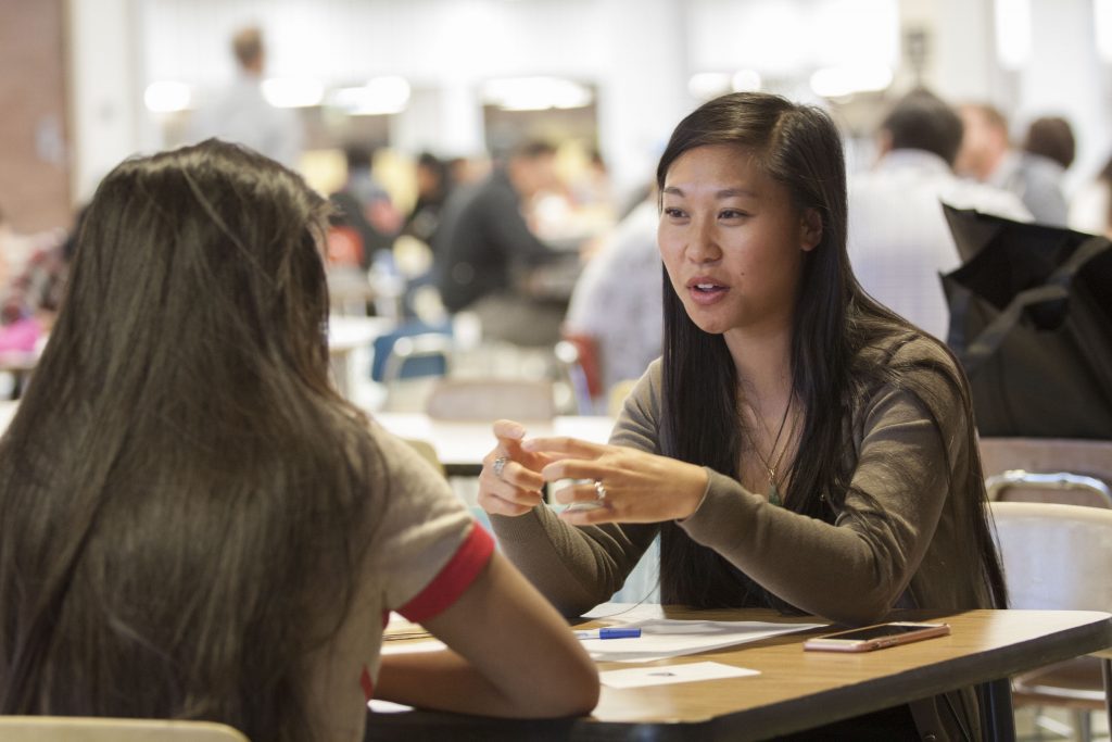 A student sitting at a table with her mentor.