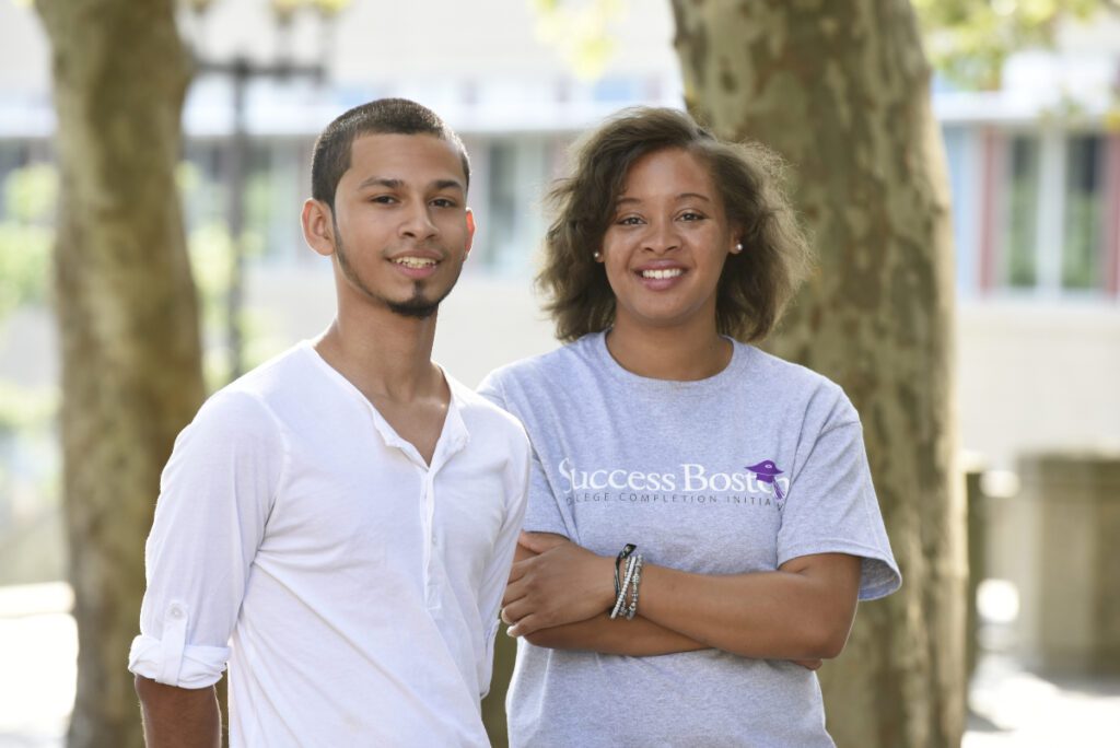 A man and a woman stand smiling at the camera