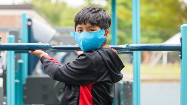 Early Childhood Education, Kid wearing a mask playing on a playground