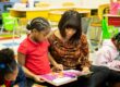 A teacher and a young girl look at a book together