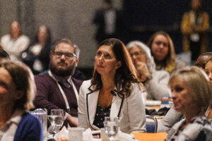 Jennifer Blatz sits at a table, listening to a presenter at the Cradle to Career Network convening.