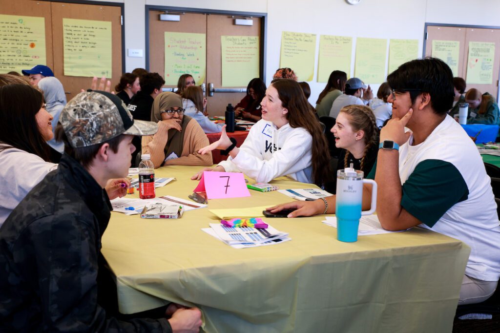 A group of five students sit around a table