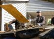 A young man is helping with disaster relief after historic flooding in southeastern Kentucky in 2022. He's tossing a piece of plywood on to a pile of debris.