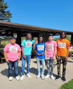 Five male students pose for a picture, wearing t-shirts from the "Back 2 School" event