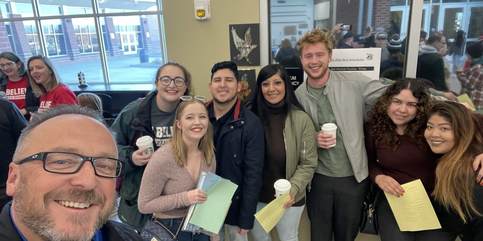 A group of eight people pose for a selfie, all smiling at the camera.