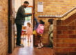 Male teacher welcoming his class with a high five outside their classroom.