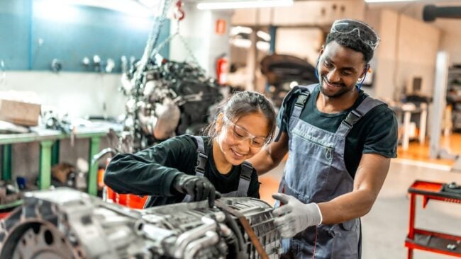 Mechanics working on vehicle engine in auto repair shop